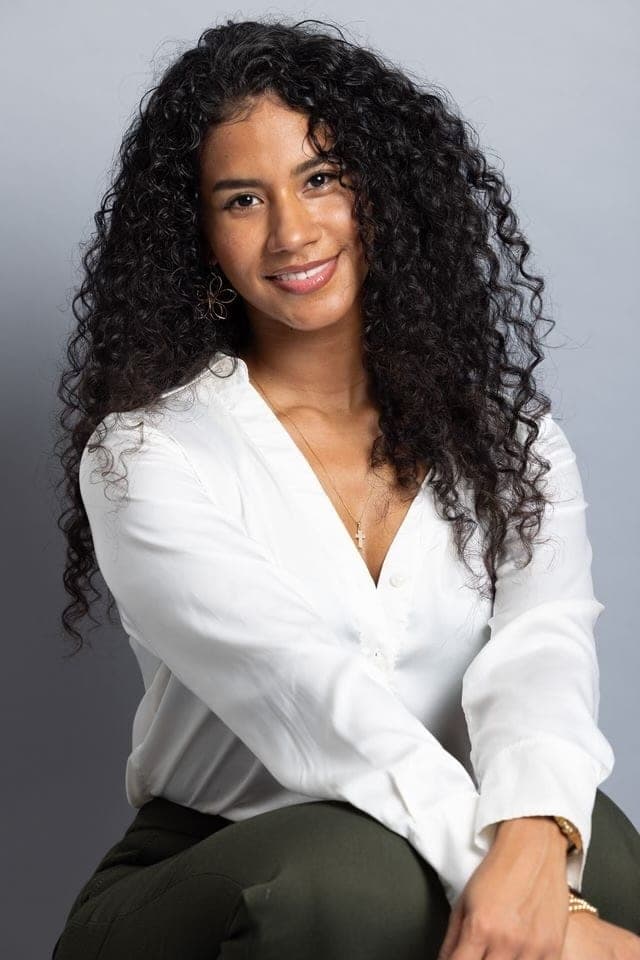 Nicol Rios seated in a white blouse and dark trousers.